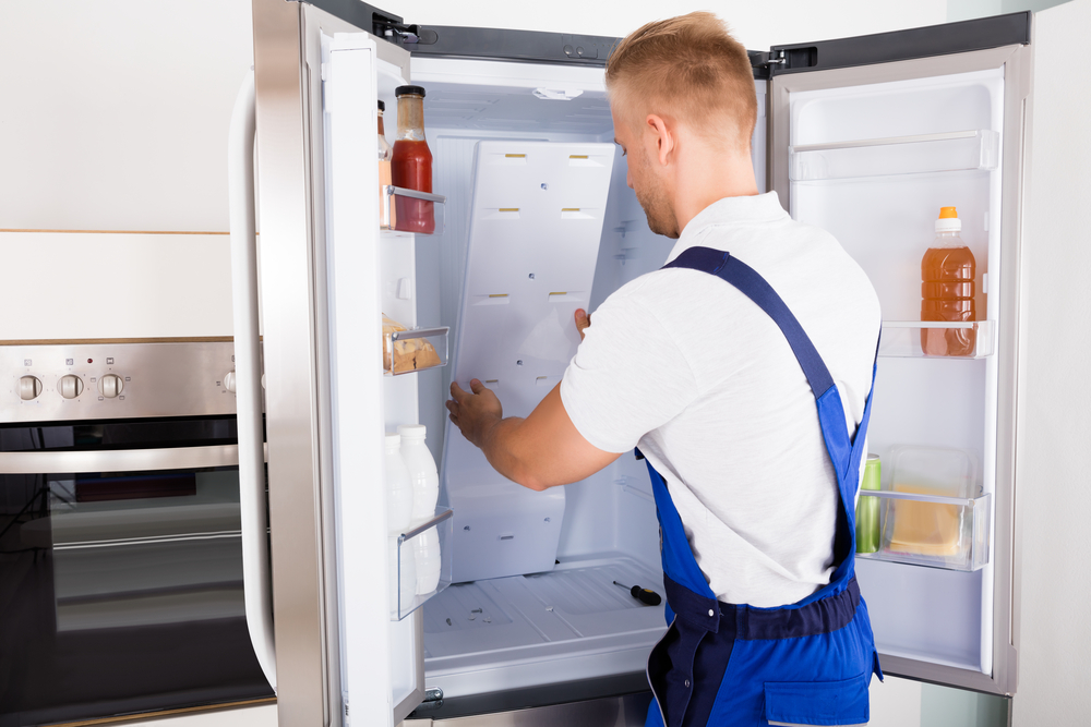 Certified technician repairing a refrigerator in Winnipeg — Appliance Repair Solution