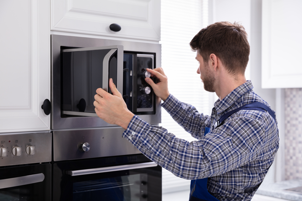 Technician repairing a built-in microwave in a Winnipeg kitchen
