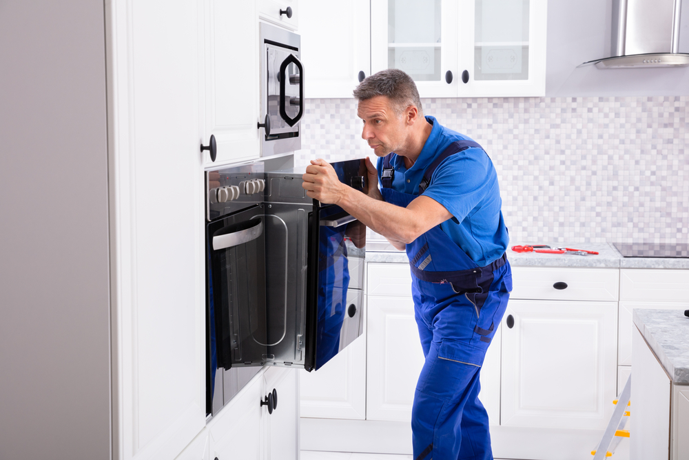 Technician inspecting and repairing an oven in a Winnipeg kitchen